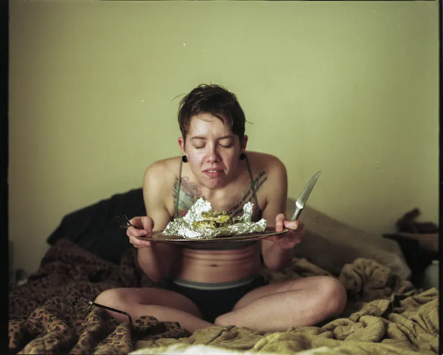 The girl leans forward as if the inhale the scent of the rotten food, holding it closer to her face.