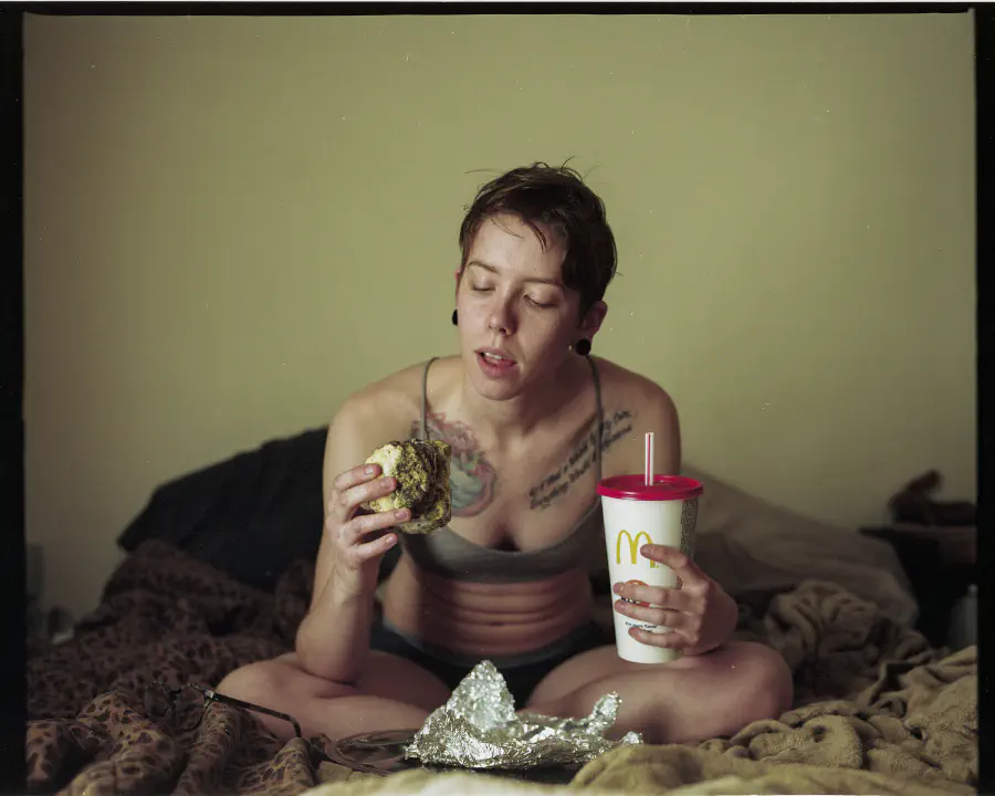 The girl holds a McDonalds beverage in one hand and the rotten food in the other.