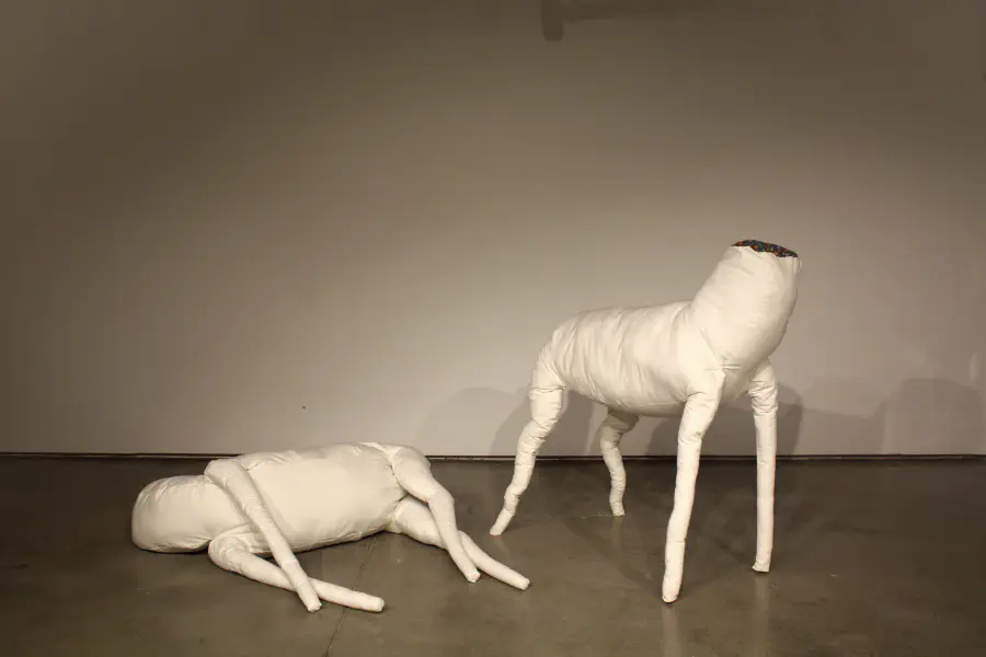 Two stuffed headless animal shapes. One is laying on the ground and the other is standing.
