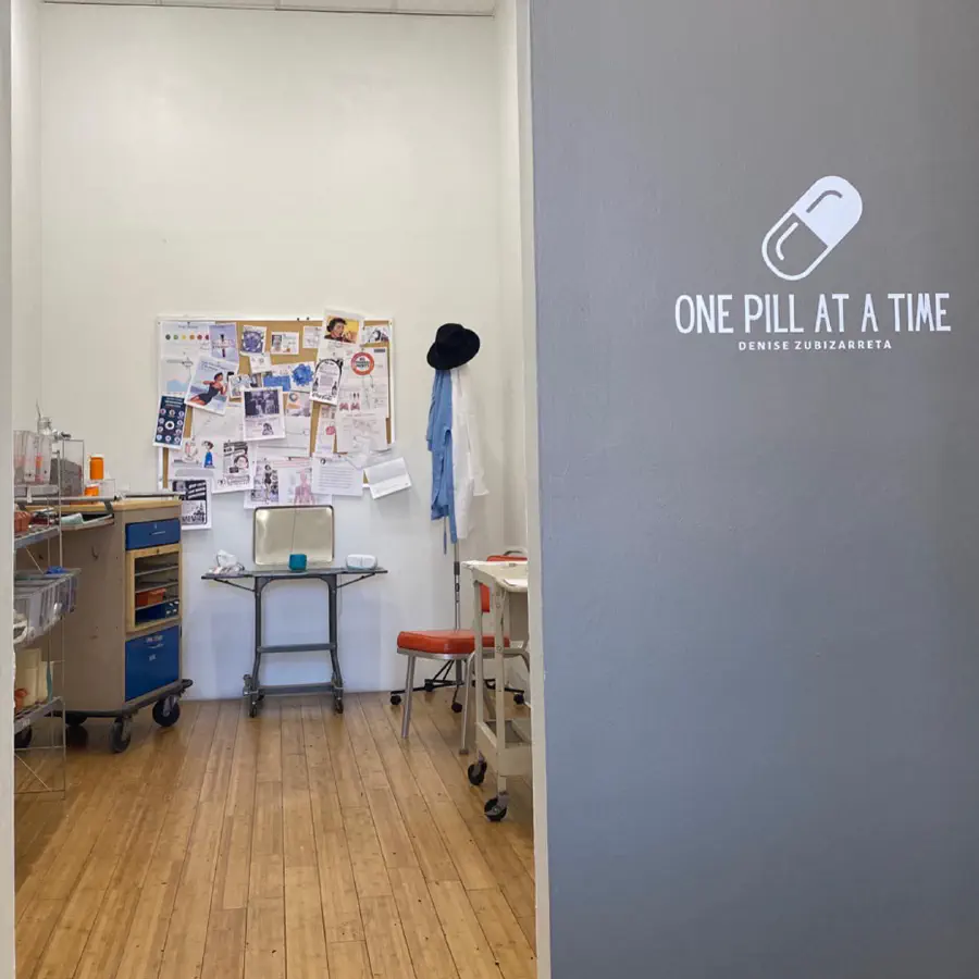 The studio with a wall covering that says 'ONE PILL AT A TIME.