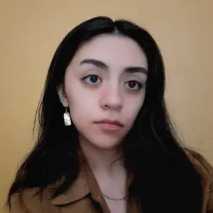 A smiling young woman with dark hair and eyes, wearing a brown blazer.